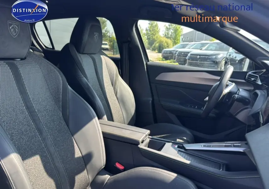 Vue intérieure côté droit de la Peugeot 308 gris, mettant en valeur les sièges sport avec logo Peugeot brodé et accoudoir central.