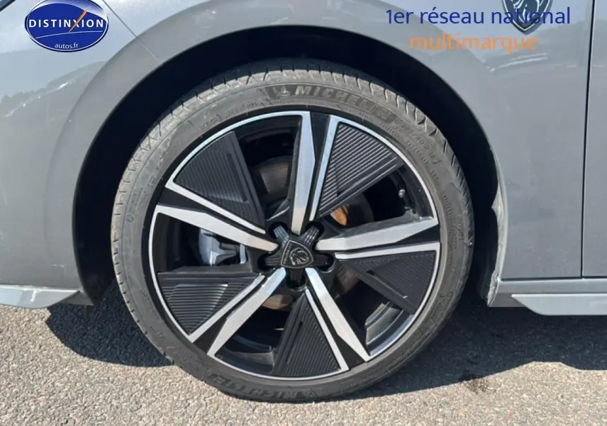 Gros plan sur la roue avant gauche d'une Peugeot 308 gris métallisé avec jante alu noire et argentée.