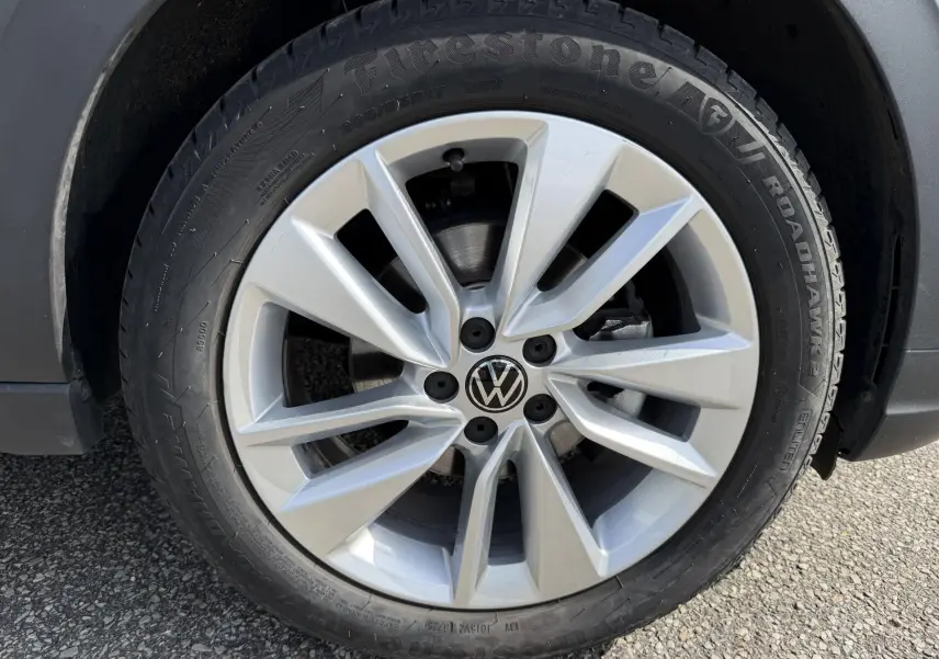 Gros plan sur la jante alliage 17 pouces argentée avec logo Volkswagen au centre du Volkswagen Taigo bleu.