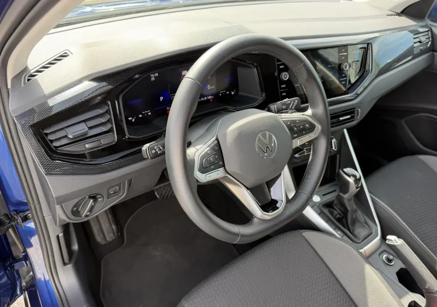 Vue intérieure côté conducteur du Volkswagen Taigo bleu 2025, volant cuir multifonctions et tableau de bord digital.