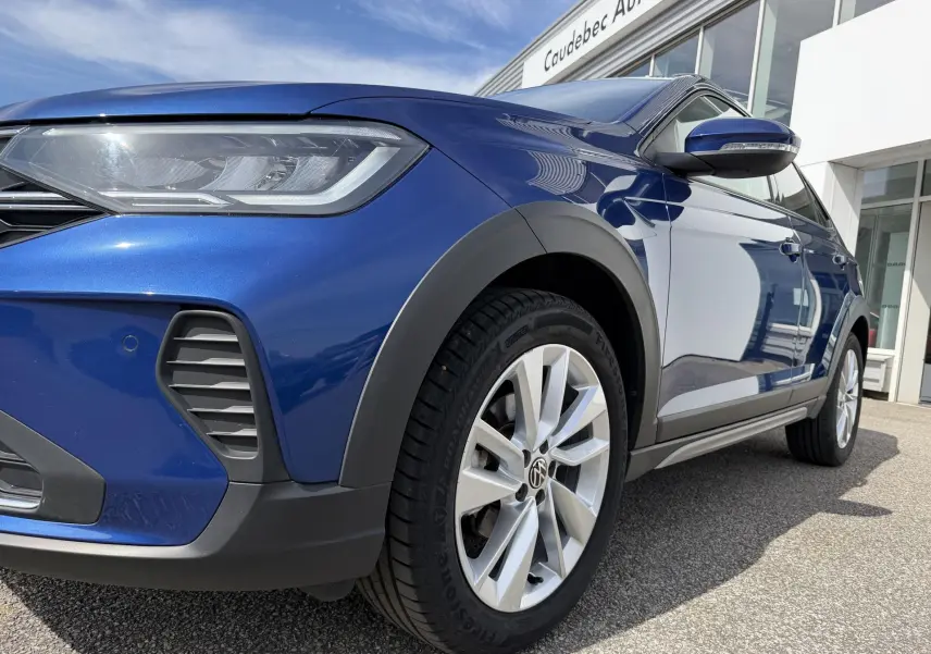 Vue en 3/4 avant droit d'un Volkswagen Taigo bleu métallisé mettant en valeur les jantes alliage 17 pouces et les phares LED.