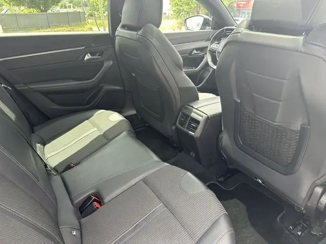 Vue intérieure arrière côté droit de la Peugeot 508 SW gris, montrant les sièges en cuir noir et les aérateurs centraux.
