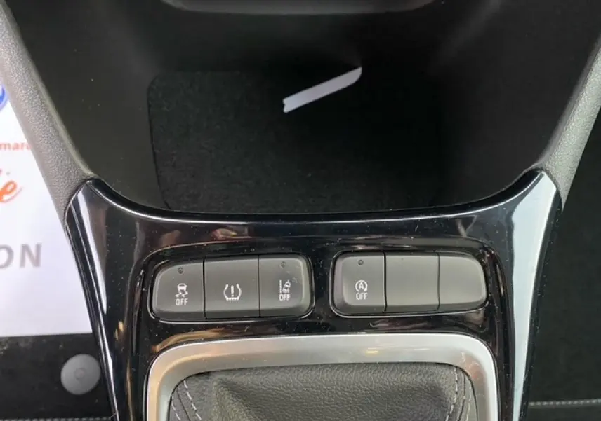 Gros plan sur la console centrale noire brillante avec commandes d'assistance et levier de vitesse en cuir.