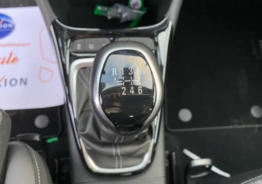 Le levier de vitesse manuel noir brillant de l'Opel Crossland 1.2i Turbo, vu en gros plan depuis l'intérieur.