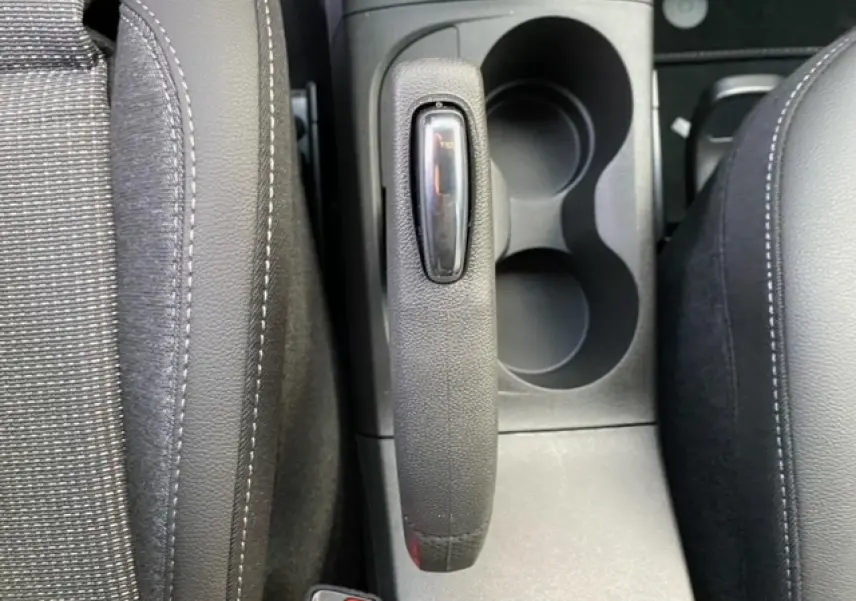 Vue rapprochée du frein à main et porte-gobelets entre les sièges avant noirs de l'Opel Crossland gris alu 2022.