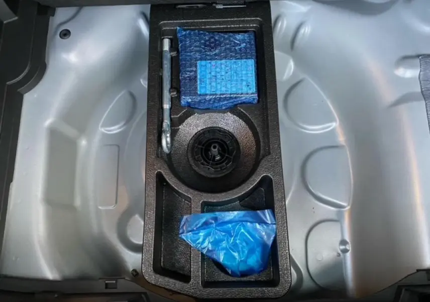 Coffre de l'Opel Crossland gris alu 2022 montrant le rangement sous le plancher avec outils et accessoires emballés.