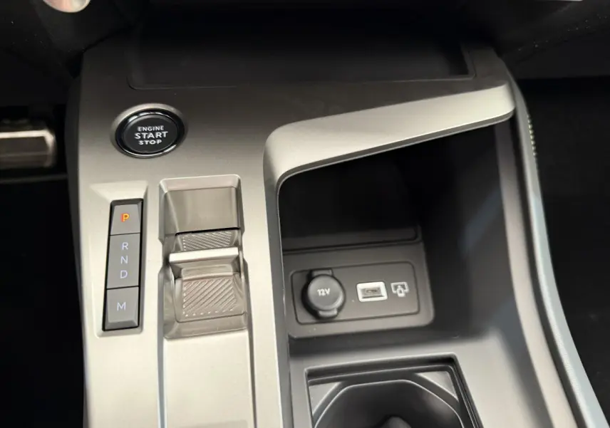 Vue rapprochée de la console centrale gris clair de la Peugeot 308 Hybrid 136 e-DCS6 GT avec bouton start et levier de vitesses automatique.