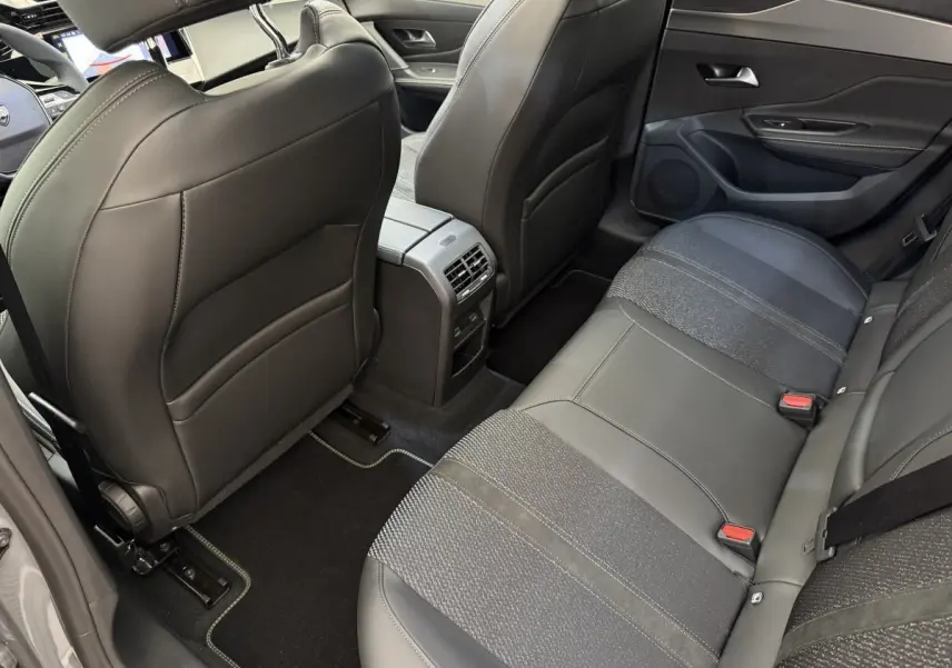 Vue arrière intérieure côté droit de la Peugeot 308 Hybrid 136 e-DCS6 GT avec sièges gris foncé en cuir et tissu.