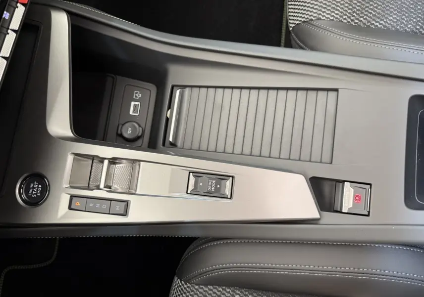 Console centrale gris clair de la Peugeot 308 Hybrid 136 e-DCS6 GT 2024 avec commandes boîte auto et bouton start/stop.
