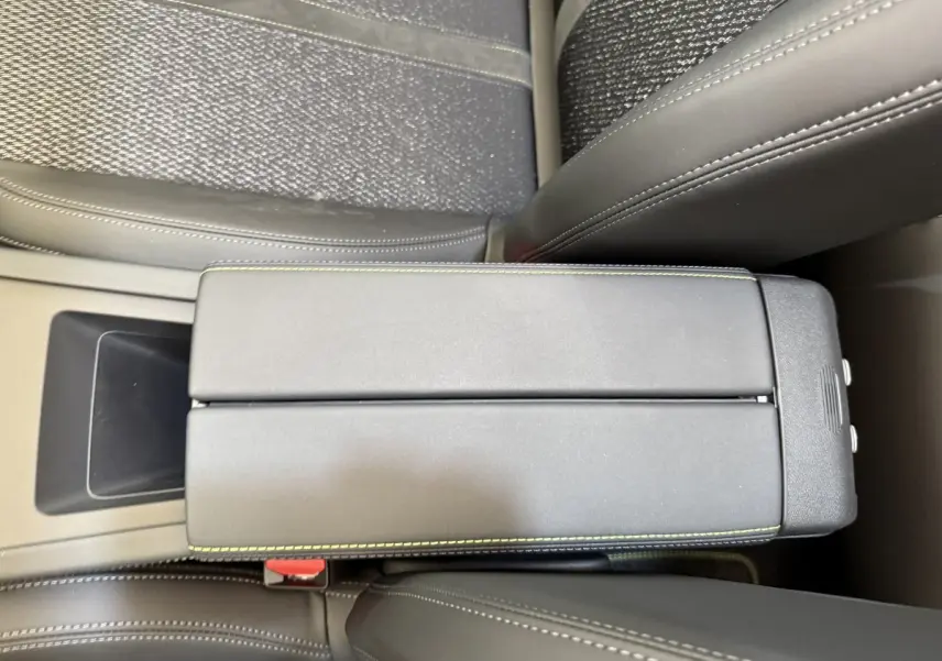 Vue rapprochée de l'accoudoir central gris foncé avec surpiqûres vertes à l'intérieur d'une Peugeot 308 Hybrid 136 e-DCS6 GT 2024.
