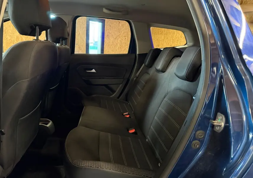 Vue latérale droite de l'intérieur arrière du Dacia Duster bleu, montrant la banquette tissu Prestige avec appuie-têtes.