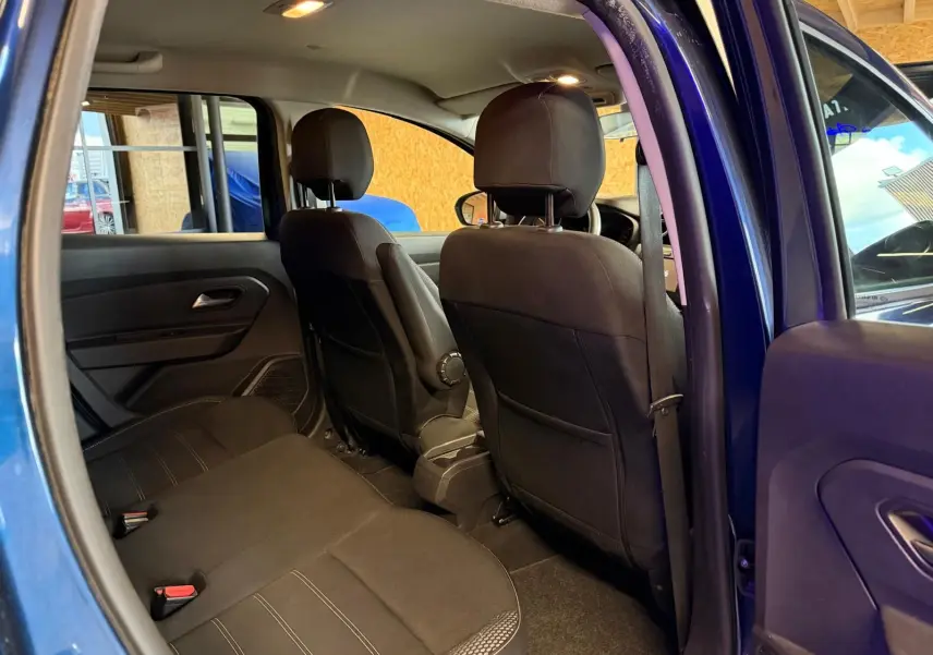 Intérieur arrière du Dacia Duster bleu, vue côté gauche avec sièges tissu noir et appuie-têtes virgulés.