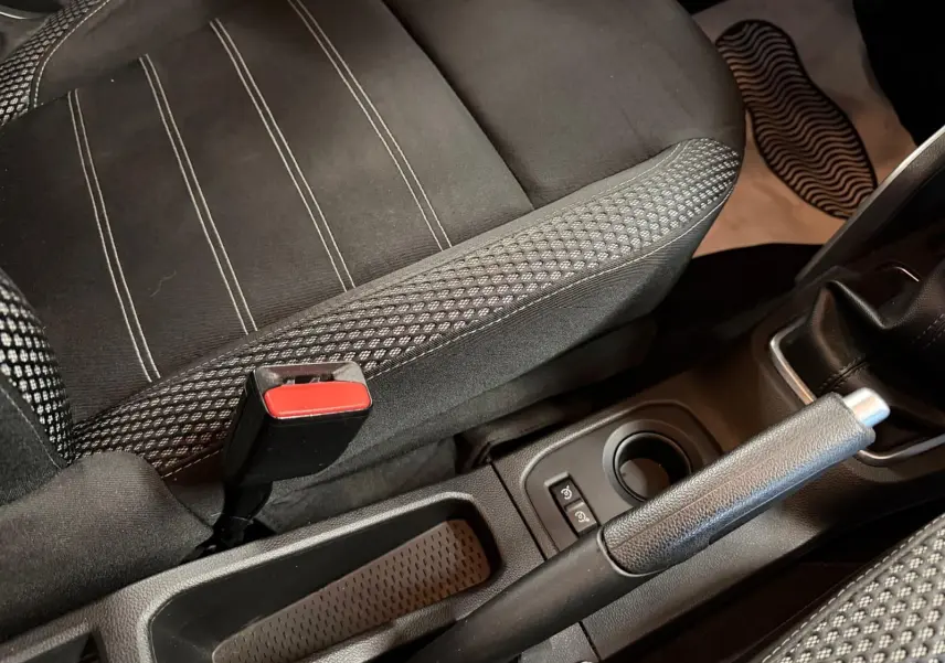 Gros plan sur la console centrale et siège tissu noir à surpiqûres du Dacia Duster bleu diesel, frein à main levé.