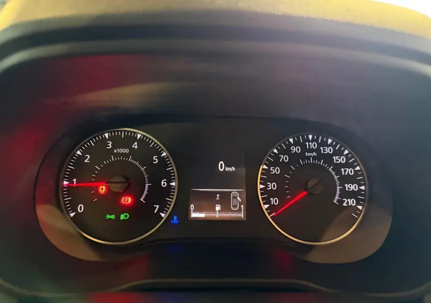 Gros plan sur le tableau de bord du Dacia Duster bleu, affichant compte-tours, vitesse et témoins lumineux actifs.