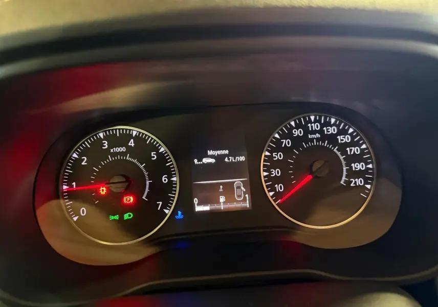 Tableau de bord du Dacia Duster bleu, affichant compte-tours, vitesse et consommation moyenne à 4,7 l/100 km.