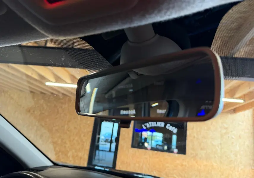 Rétroviseur intérieur du Dacia Duster bleu, vue rapprochée avec reflet d'une porte et d'un panneau lumineux.