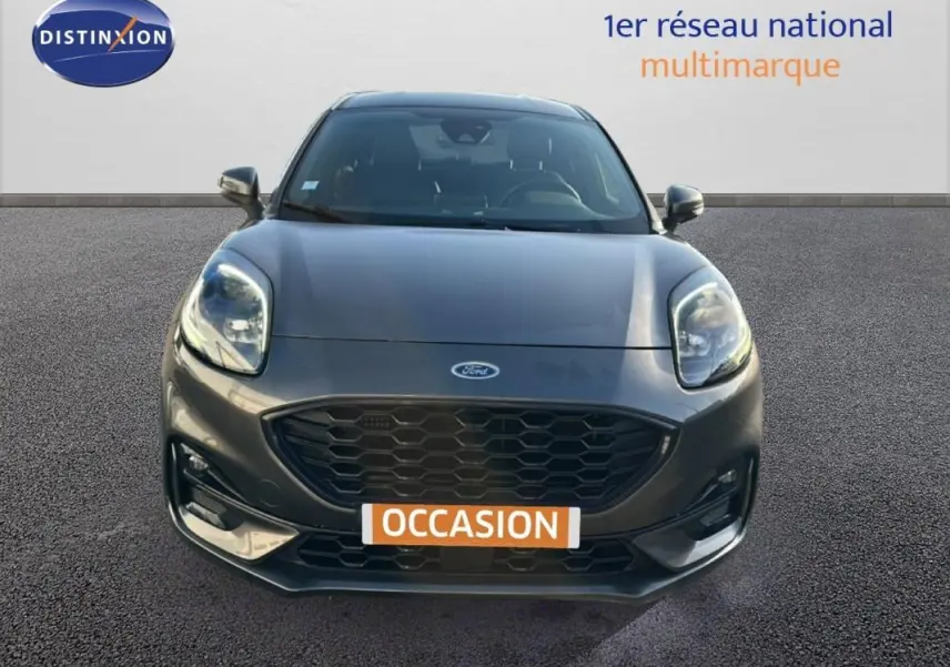 Vue avant d'une Ford Puma gris foncé avec calandre noire et feux allumés sur fond neutre.