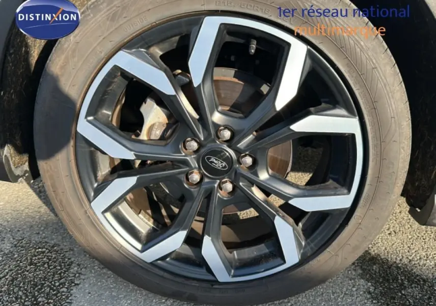 Gros plan sur la jante alliage 18 pouces noire et argentée du Ford Puma gris foncé, roue avant droite visible.