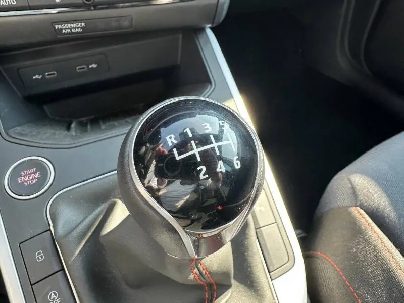 Gros plan sur le levier de vitesse manuel noir avec coutures rouges dans l’habitacle du SEAT Arona 2025.