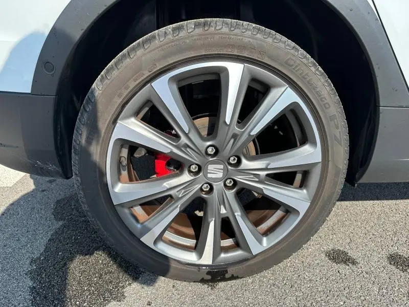 Gros plan sur la roue avant droite du SEAT Arona blanc Candy avec jante alliage grise et étrier de frein rouge visible.