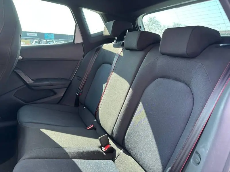 Vue intérieure arrière côté droit du SEAT Arona 2025, sièges noirs avec surpiqûres rouges et appuie-têtes intégrés.