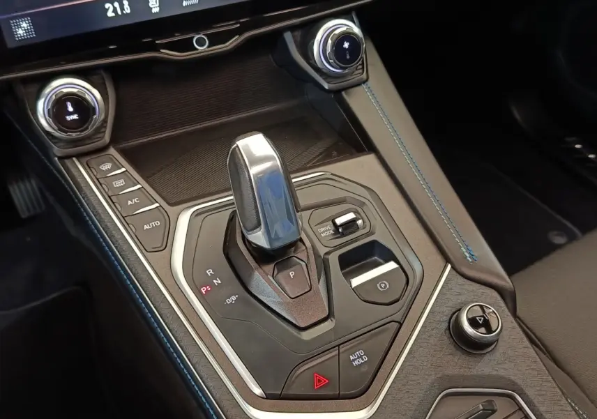 Gros plan sur la console centrale du LINK & CO 01 hybride rechargeable 2023, avec levier de vitesses et surpiqûres bleues.