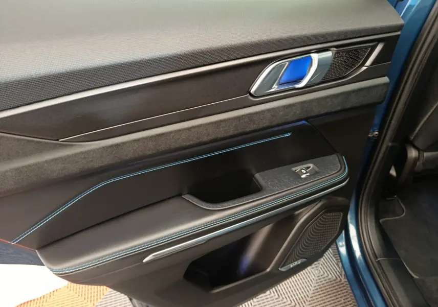 Gros plan sur la porte avant gauche bleu du LINK & CO 01 avec surpiqûres bleues et poignée métallique.