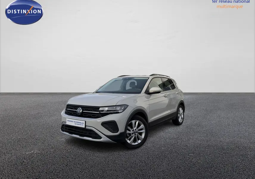 Volkswagen T-Cross gris vue 3/4 avant droit sur sol gris, avec jantes alliage et calandre noire distinctive.