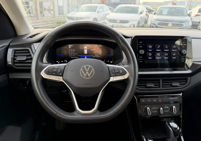 Vue intérieure centrée sur le volant cuir multifonction et l'écran tactile du tableau de bord du Volkswagen T-Cross gris.