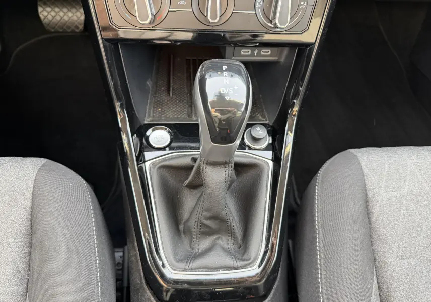 Gros plan sur la console centrale du Volkswagen T-Cross gris 2025, avec levier de vitesse DSG7 et commandes de climatisation.