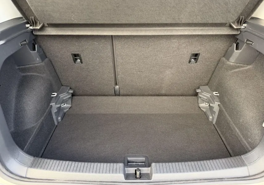 Coffre ouvert du Volkswagen T-Cross gris, vue de l'intérieur montrant un espace de rangement propre et bien fini.