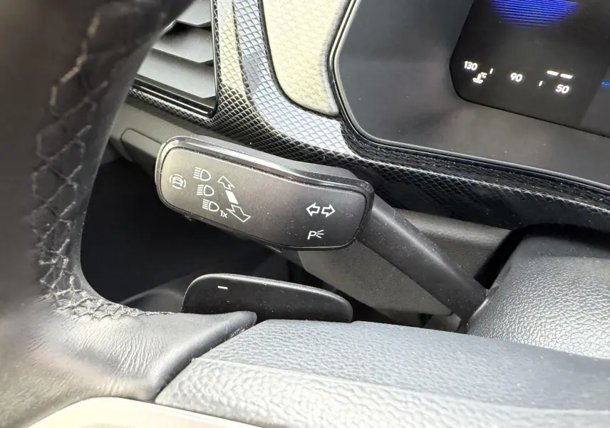 Gros plan sur la manette de clignotants et le volant en cuir à l'intérieur d'un Volkswagen T-Cross gris.