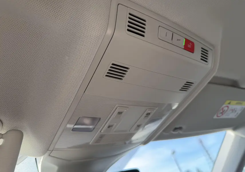 Vue intérieure du plafonnier gris clair du Volkswagen T-Cross 2025 avec boutons d'éclairage et alerte SOS visible.