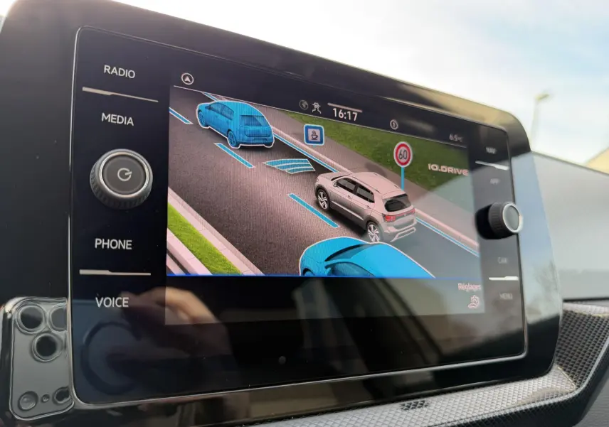 Écran tactile intérieur montrant l'aide au maintien de voie avec représentation graphique d'un Volkswagen T-Cross gris.