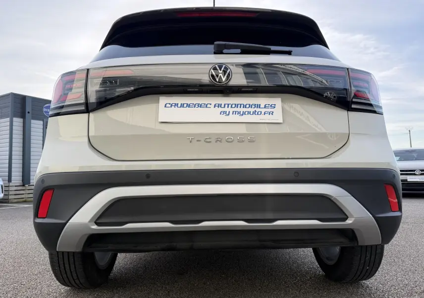 Vue arrière d'un Volkswagen T-Cross gris avec feux LED et logo VW visible sur un parking extérieur.