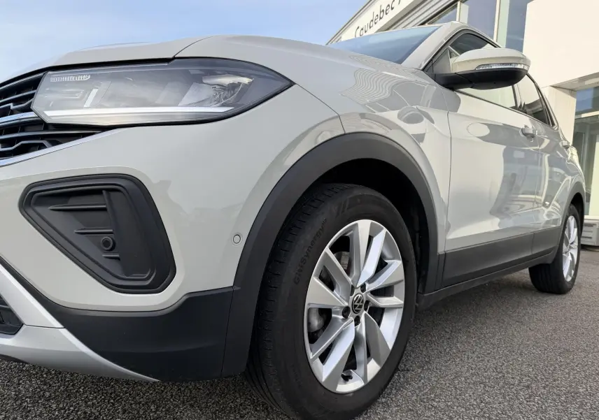 Vue 3/4 avant droit du Volkswagen T-Cross gris avec jantes alliage et projecteurs LED visibles.