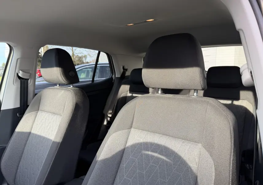 Vue intérieure sur les sièges avant gris tissu du Volkswagen T-Cross, avec banquette arrière partiellement visible.