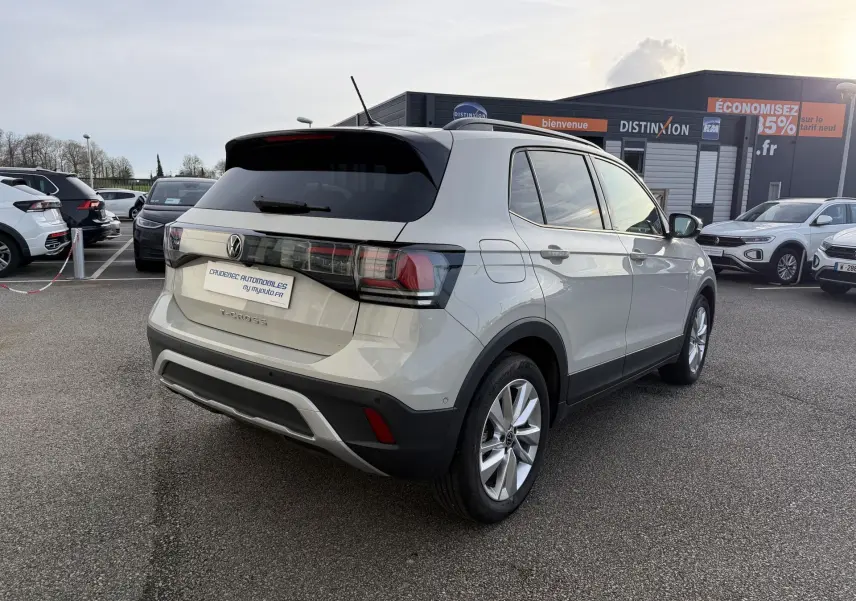 Vue 3/4 arrière droite d'un Volkswagen T-Cross gris avec jantes alliage, garé en extérieur sur un parking.