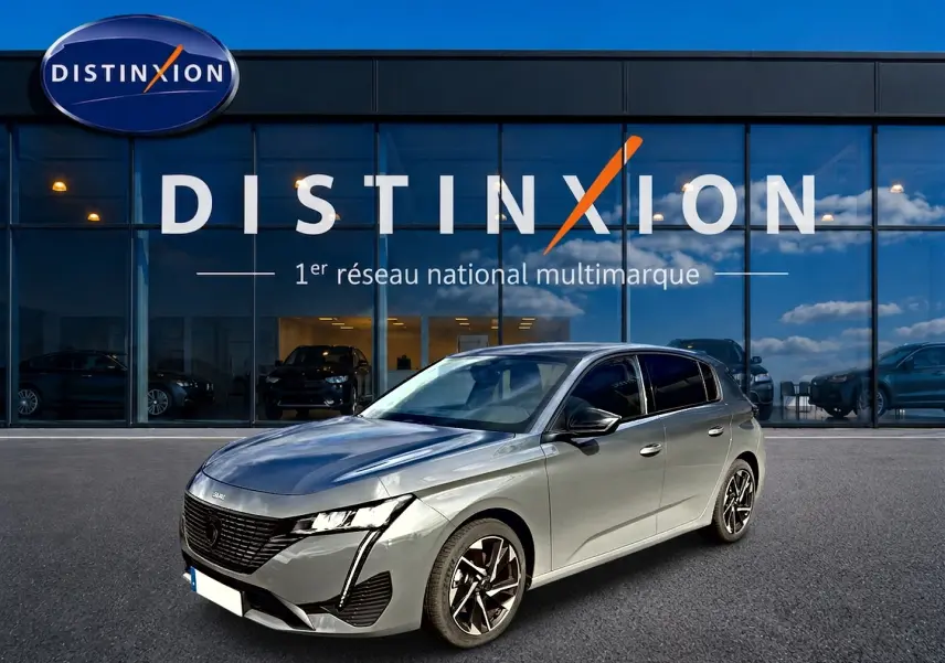 Peugeot 308 gris selenium vue 3/4 avant droit devant une vitrine Distinxion avec jantes alu noires.