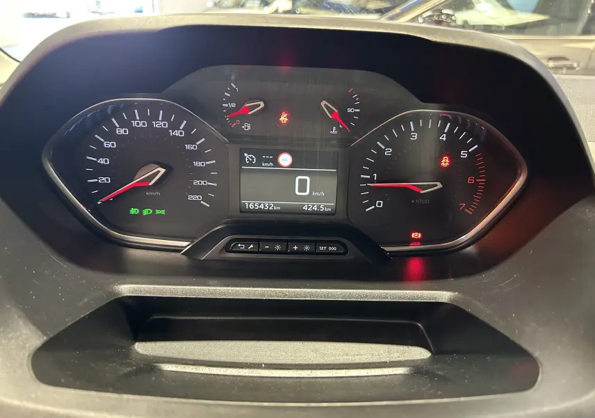 Vue rapprochée du tableau de bord du Peugeot Rifter gris sable, affichant le compteur et les voyants allumés.