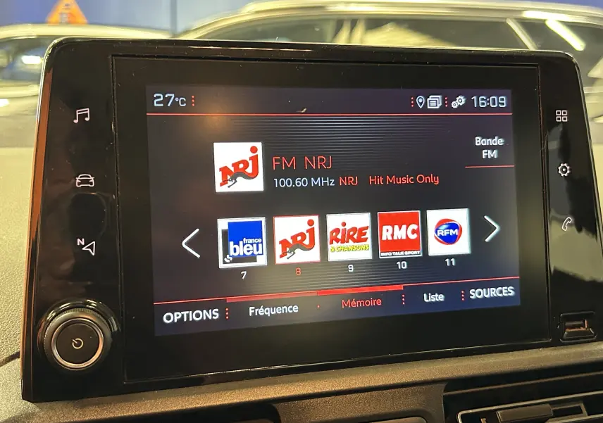 Écran tactile du système GPS du Peugeot Rifter 2019 affichant les stations radio FM, avec tableau de bord en arrière-plan.