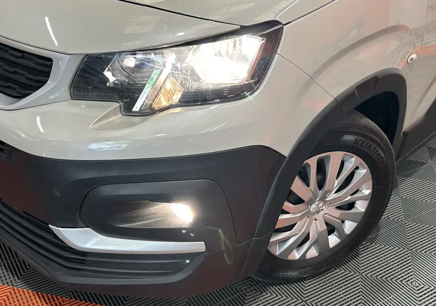 Gros plan sur l'avant droit gris sable du Peugeot Rifter 2019 avec phare et antibrouillard allumés.