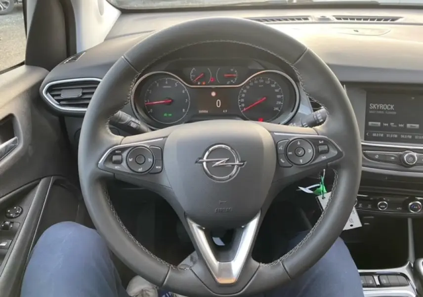 Vue centrée sur le volant cuir noir de l'Opel Crossland 2022, avec tableau de bord et écran multimédia en arrière-plan.