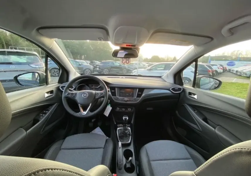 Vue intérieure avant de l'Opel Crossland noir métal 2022, avec tableau de bord moderne et boîte manuelle visible.