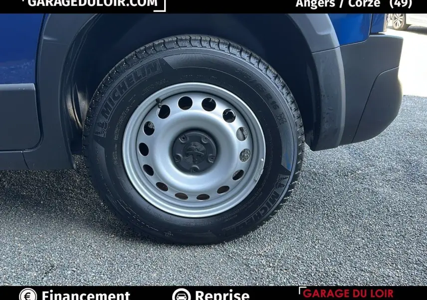 Gros plan sur la roue avant droite en jante tôle argentée du Peugeot Rifter bleu 2024.