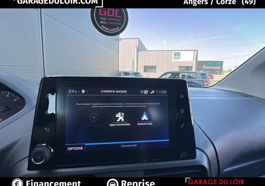 Vue intérieure centrée sur l'écran tactile 10'' du Peugeot Rifter bleu, avec tableau de bord et pare-brise visibles.
