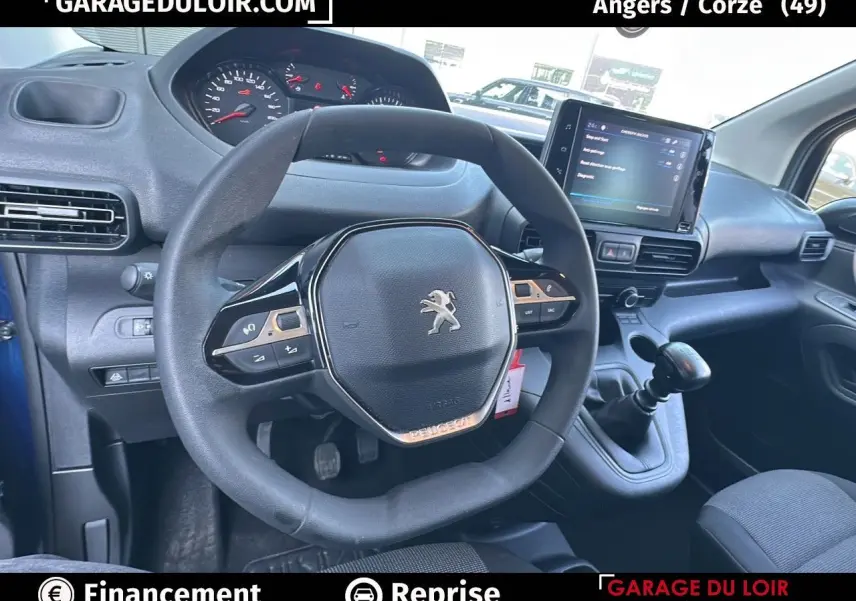 Vue intérieure du volant cuir multifonction et tableau de bord numérique du Peugeot Rifter bleu 2024 avec boîte manuelle.