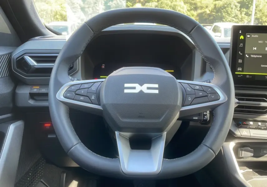 Vue rapprochée du volant cuir et du tableau de bord digital du Dacia Bigster Hybrid 155 Journey City 2025.
