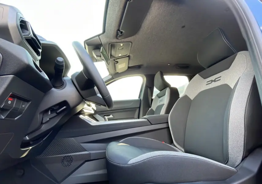 Intérieur du Dacia Bigster Hybrid 155 Journey City, vue côté conducteur sur les sièges bi-matière avec logo DC brodé.