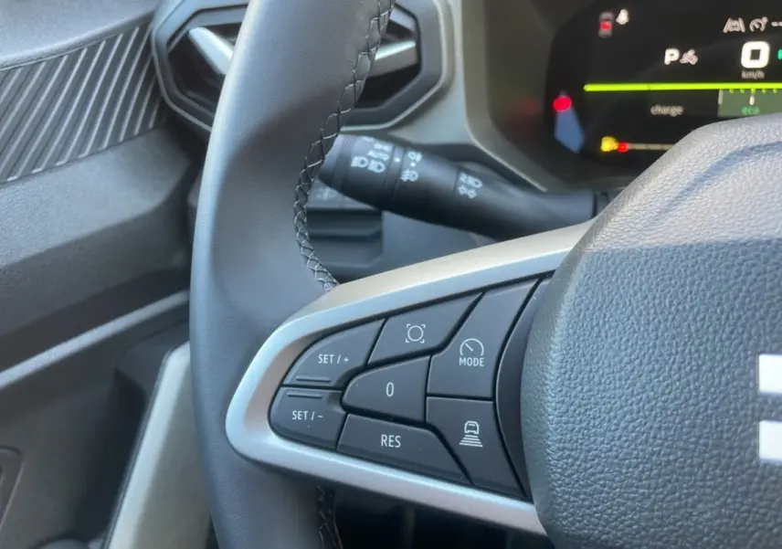 Gros plan sur les commandes au volant cuir du DACIA Bigster Hybrid 155 Journey City, tableau de bord digital en arrière-plan.